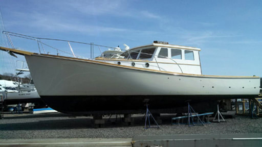 twist wooden downeast power yacht on boat stands being refit and restored by south shore boatworks