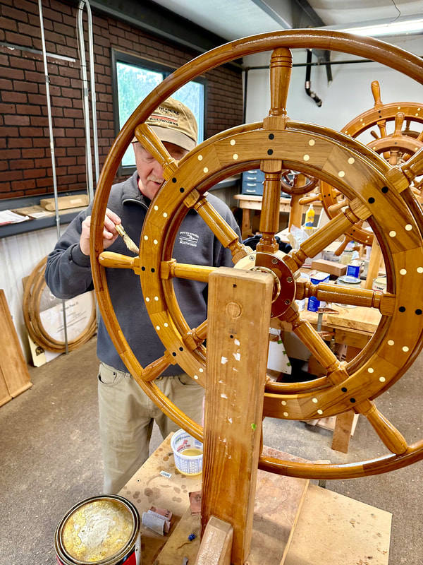 Bob Fuller of South Shore Boatworks measuring a wooden yacht steering wheel in preparation for final assembly and construction