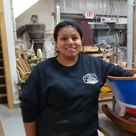 Christina fuller of south shore boatworks portrait next to a plymouth rock'r wooden rocking boat in the shop
