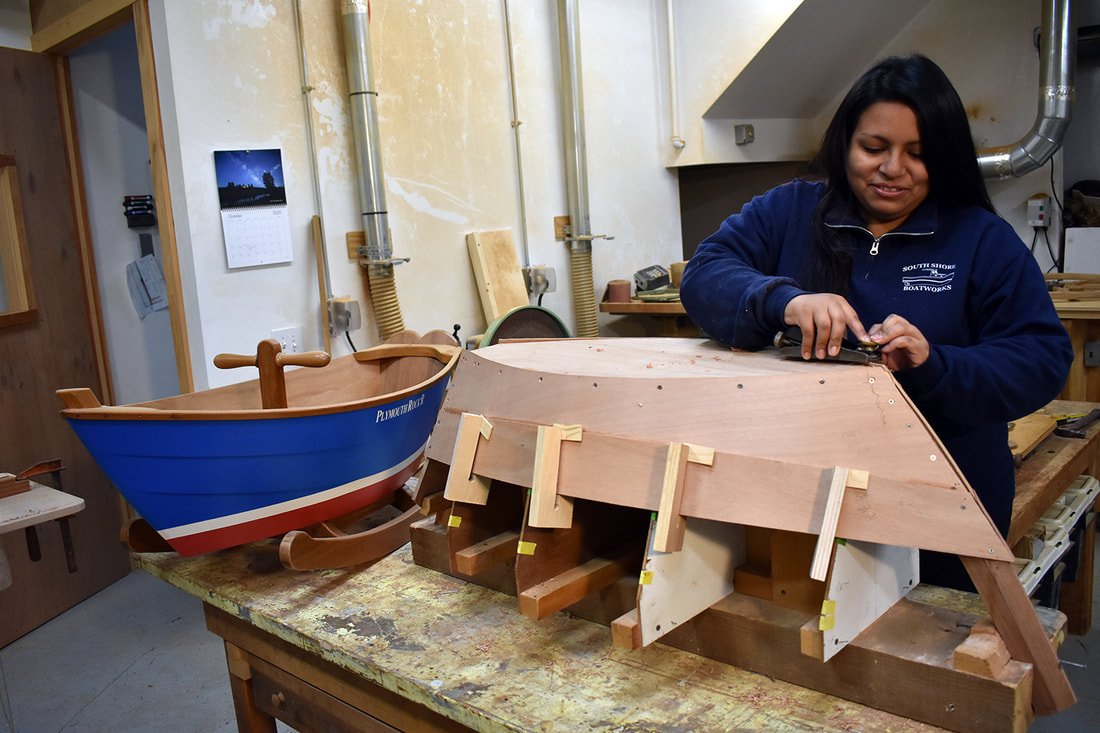 Christina Fuller building a plymouth rock'r children's wooden rocking boat in the South Shore Boatworks shop