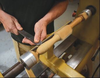 bob fuller of south shore boatworks using a lathe to turn wooden spokes for a traditional wooden yacht ship steering wheel