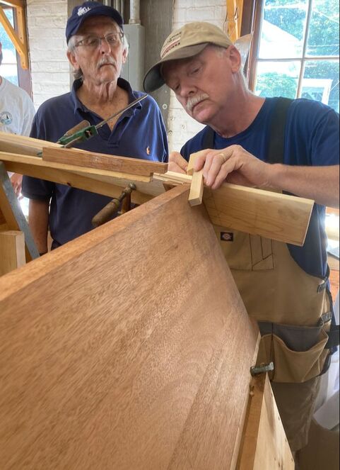 Bob Fuller of South Shore Boatworks teaching a student how to build a wooden boat by scribing the angle of a plank