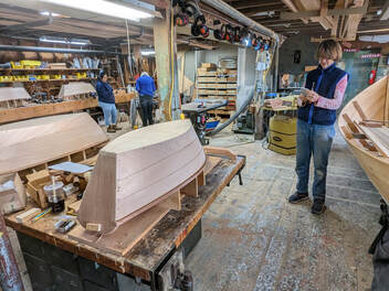 A wood shop with plymouth rock'r wooden rocking boats still on their frames as Bob Fuller of south shore boatworks instructs students how to build them in his class