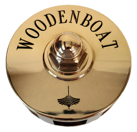 polished bronze wheel hub engraved with woodenboat logo and bronze wheel nut crafted by south shore boatworks for sailing yacht or ship