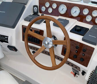 wooden powerboat steering wheel built by south shore boatworks in teak with finger grips in the performance plus design installed on helm