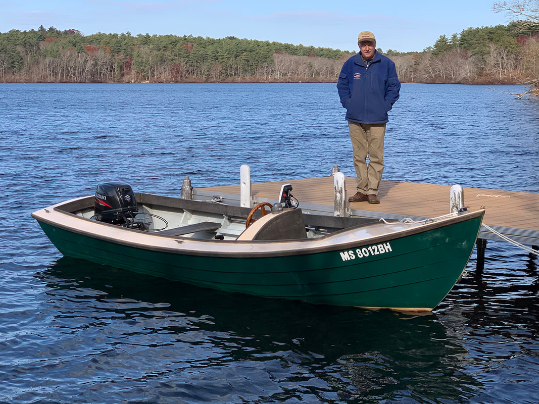 Bob Fuller on dock next to 18 foot wooden simmons sea skiff power boat built by south shore boatworks